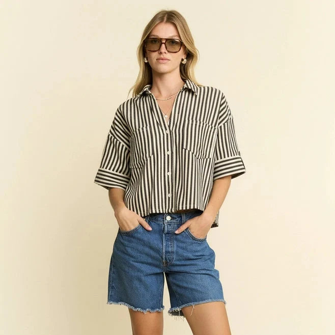 Woman wearing a striped shirt and denim shorts against a beige background
